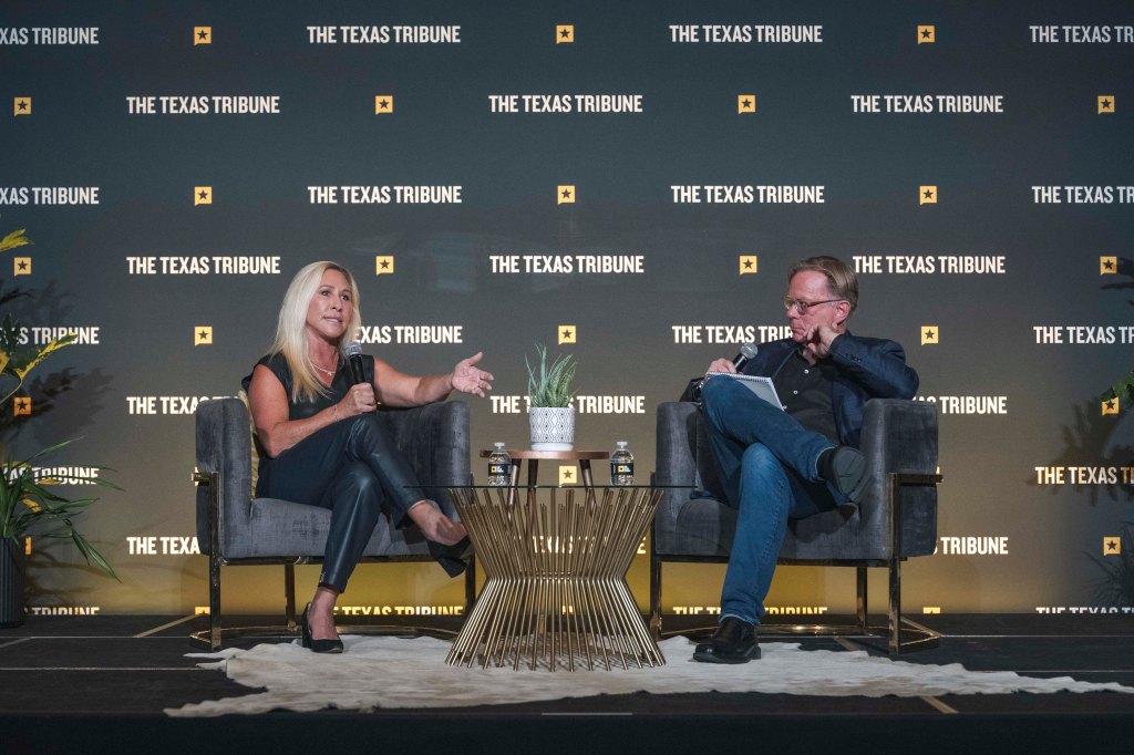 Two individuals seated on stage during a discussion event, with a backdrop featuring The Texas Tribune logo.